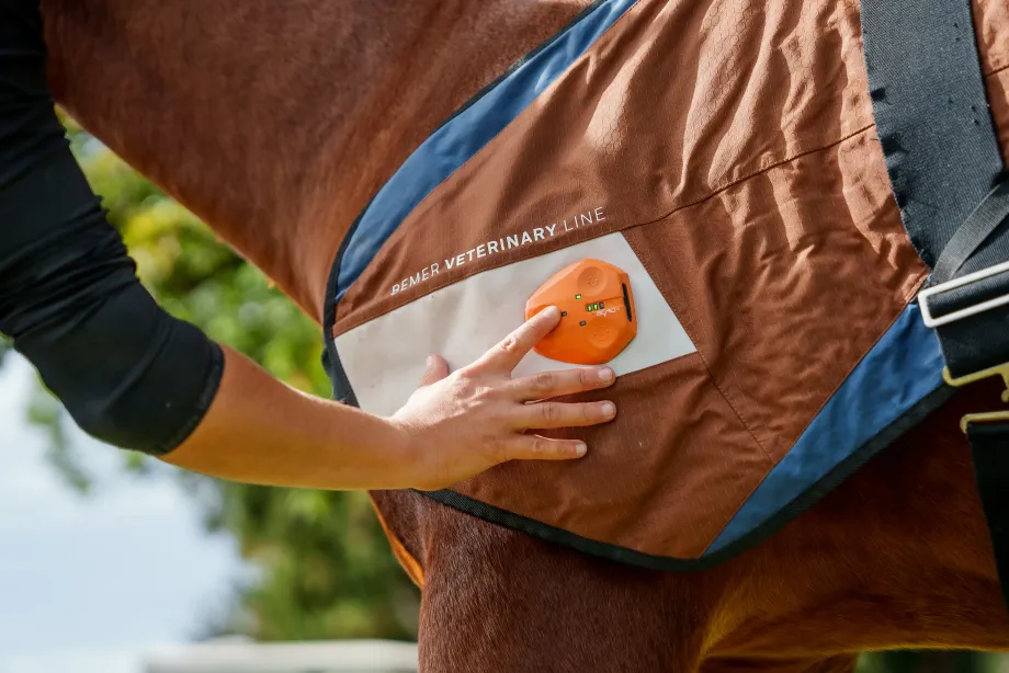 Hand bedient ein orangefarbenes Gerät an einer BEMER-Decke für Rehatherapie
